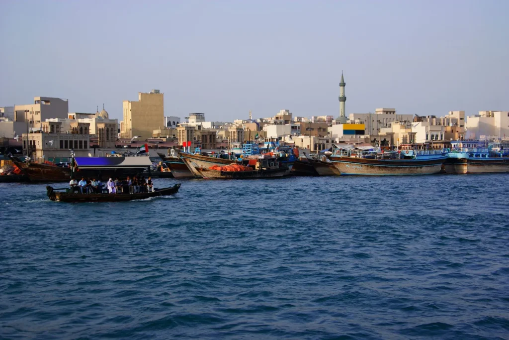 Traditional abra boat crossing Dubai Creek with Deira souk in the background — best place to stay in Dubai for culture and authentic old city experience